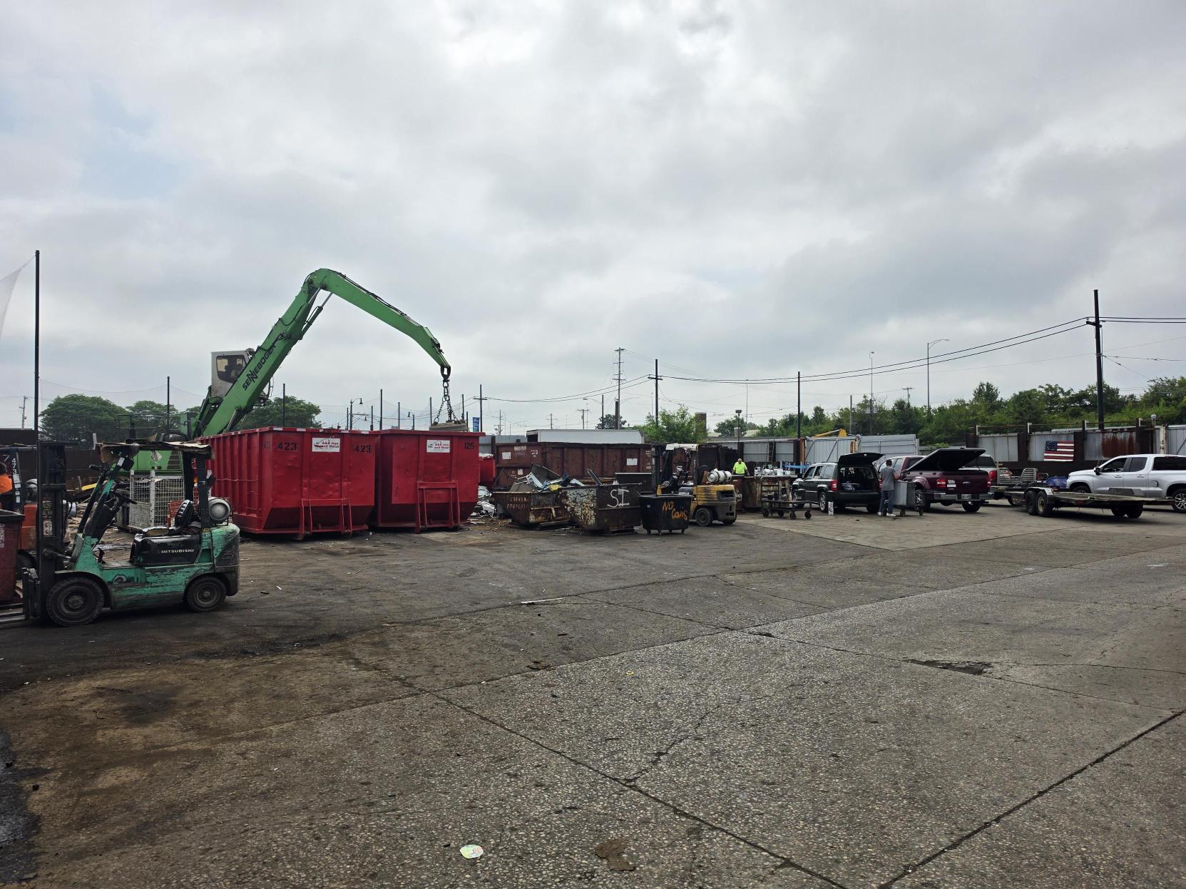 Material handler loading roll-off containers while customers unload at the A&B Iron and Metal yard